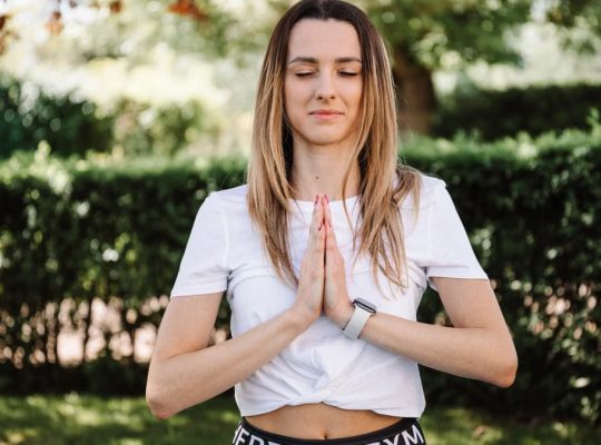 A serene moment of a woman practicing yoga with namaste pose outdoors, embracing mindfulness.