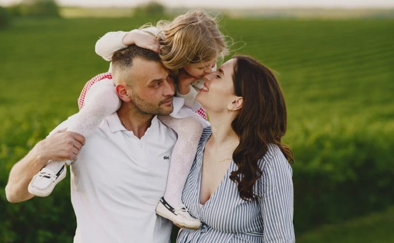 A delightful family moment captured in a lush scenic field, portraying love and happiness.